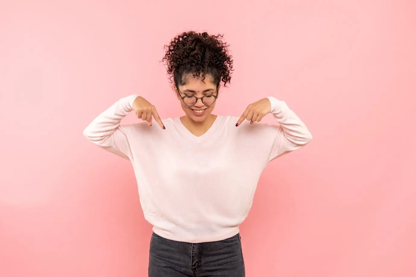 Front-facing view of a smiling young woman against a pink wall
